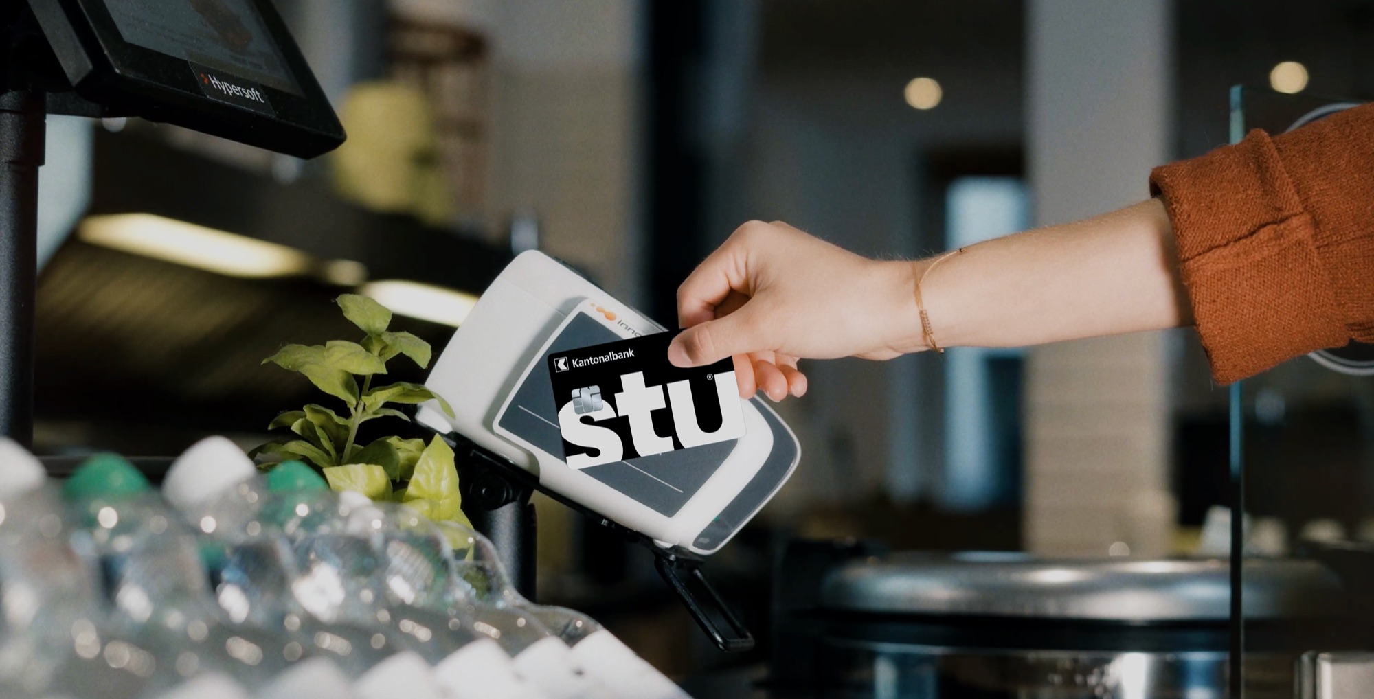 Junge Person bezahlt mit der Stu-Karte der Kantonalbank am Terminal